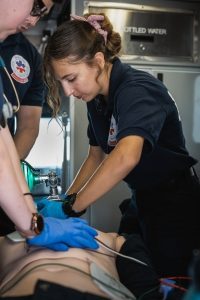 EMT delivering CPR First Aid AED training inside ambulance